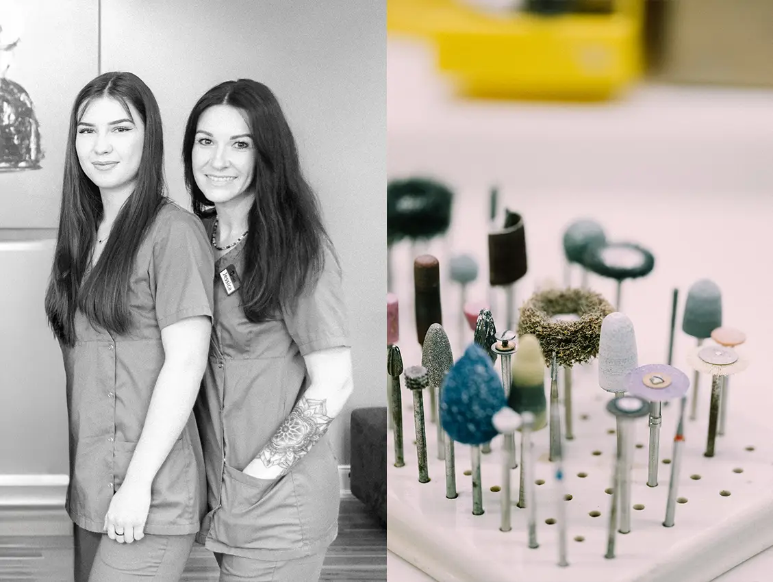 Zwei Frauen in Praxisbekleidung stehen lächelnd nebeneinander während daneben verschiedene Dentalinstrumente in einer Halterung zu sehen sind