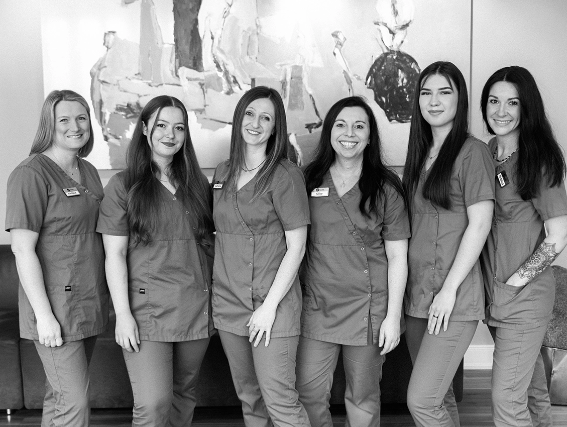 Praxisteam steht gemeinsam und lächelt in die Kamera