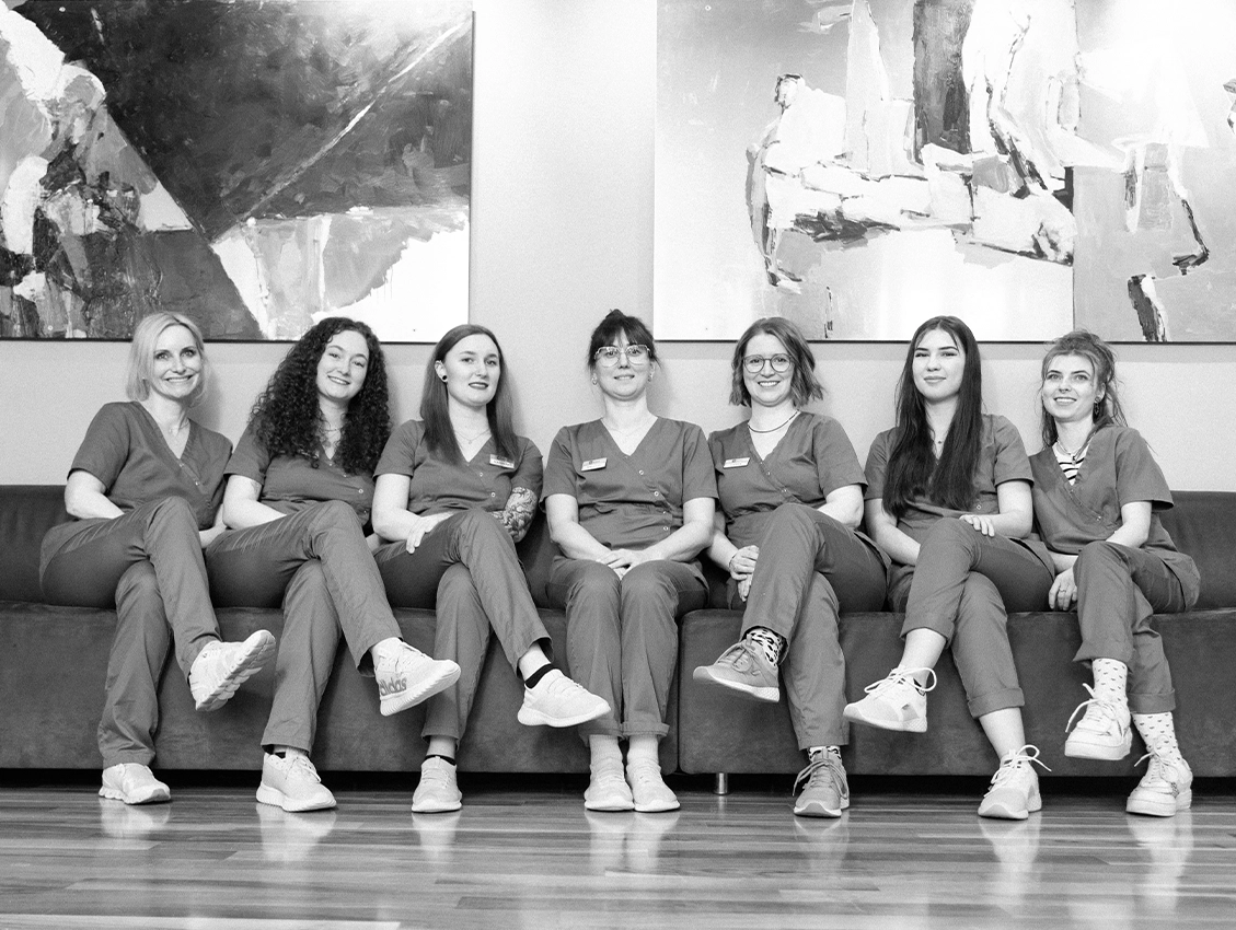 Praxisteam sitzt gemeinsam auf einem Sofa und lächelt